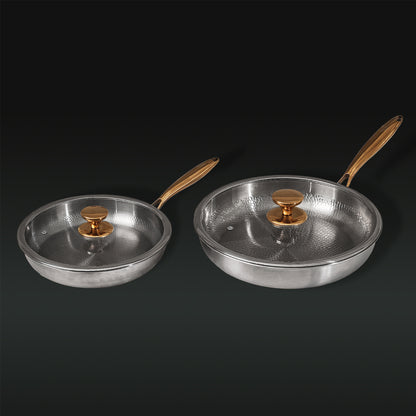 Two Titanium frying pans with golden handles on a black background