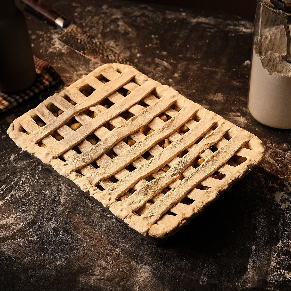 Unbaked pie with a lattice top on a dark surface